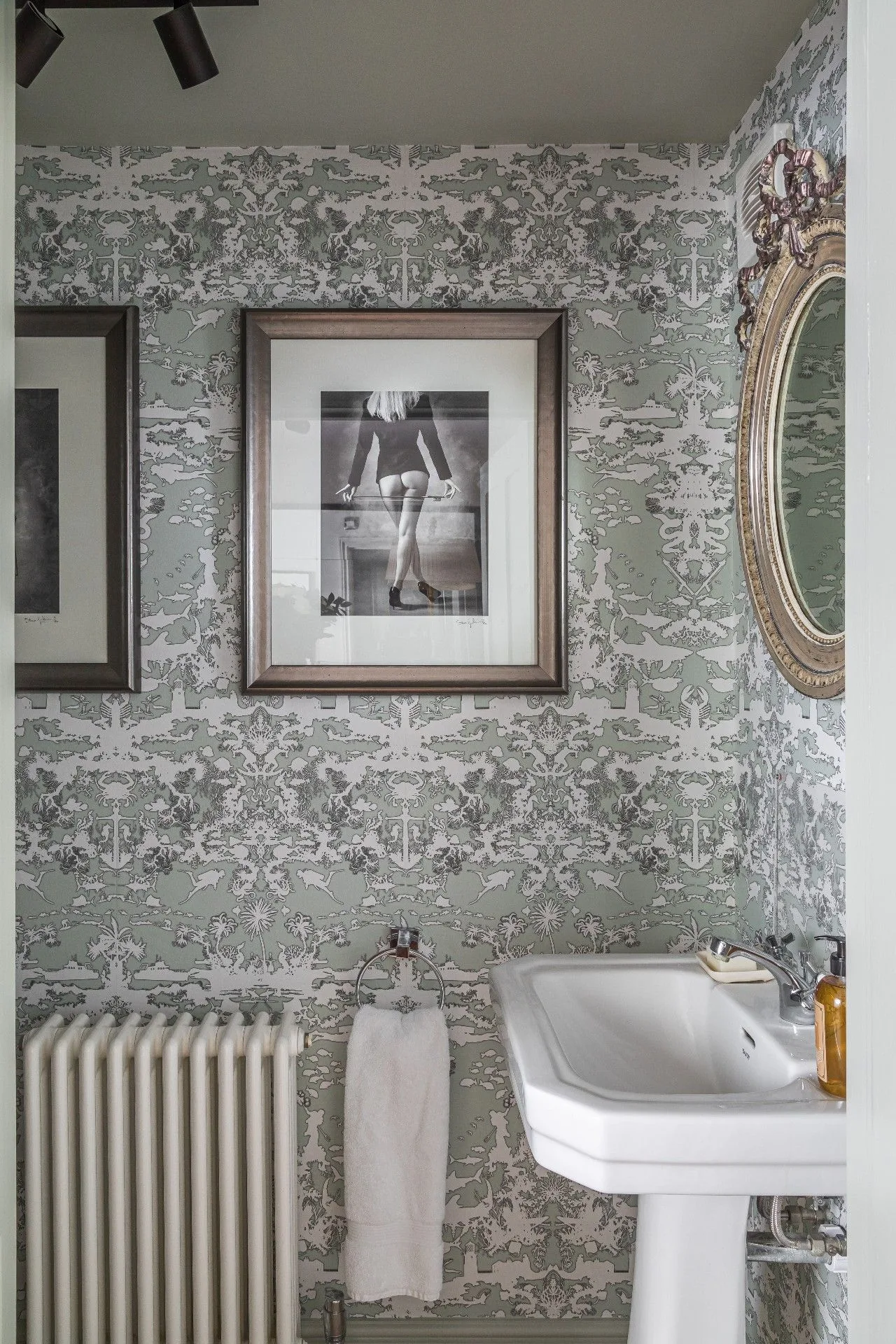 Gray patterned powder room with white pedestal basin, framed photographs and radiator