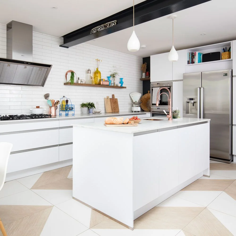 White handleless-style drawers and a matching island have continuous recessed horizontal channels beneath dark ceiling beams.