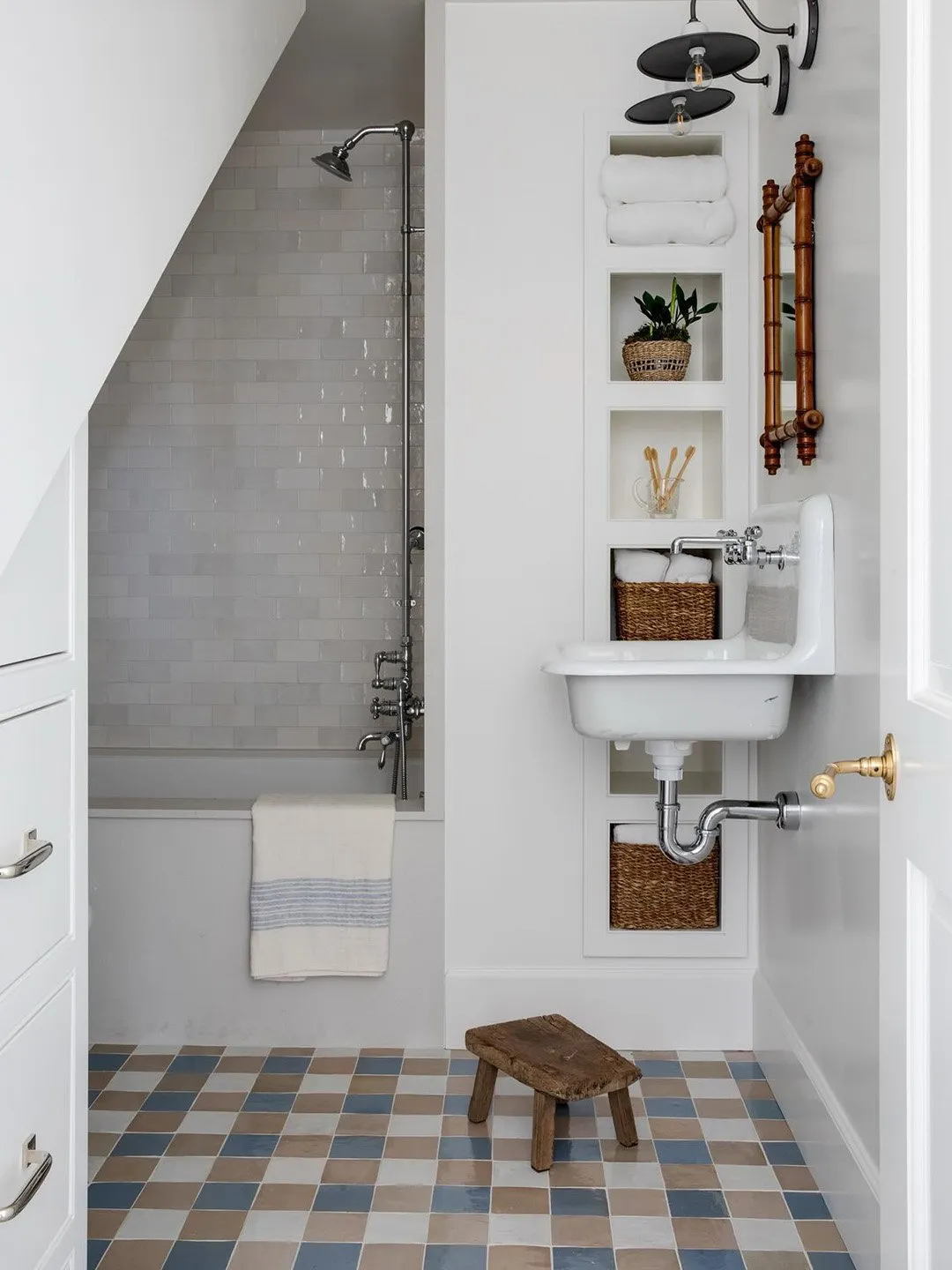 Muted blue, beige, and gray squares cover a small white bathroom floor