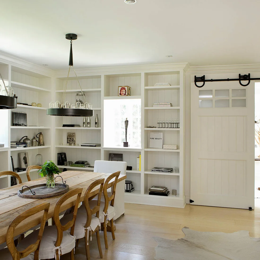 White open dining shelves around a narrow bright opening beside a long wood table and sliding door