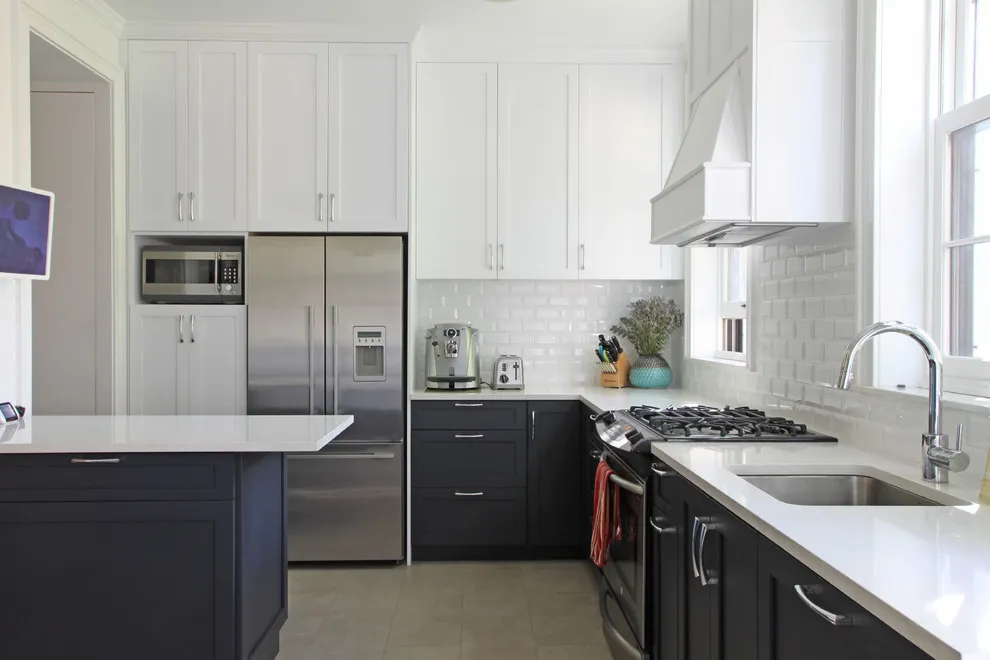 White upper cabinets sit over dark lower doors beside a bright sink window