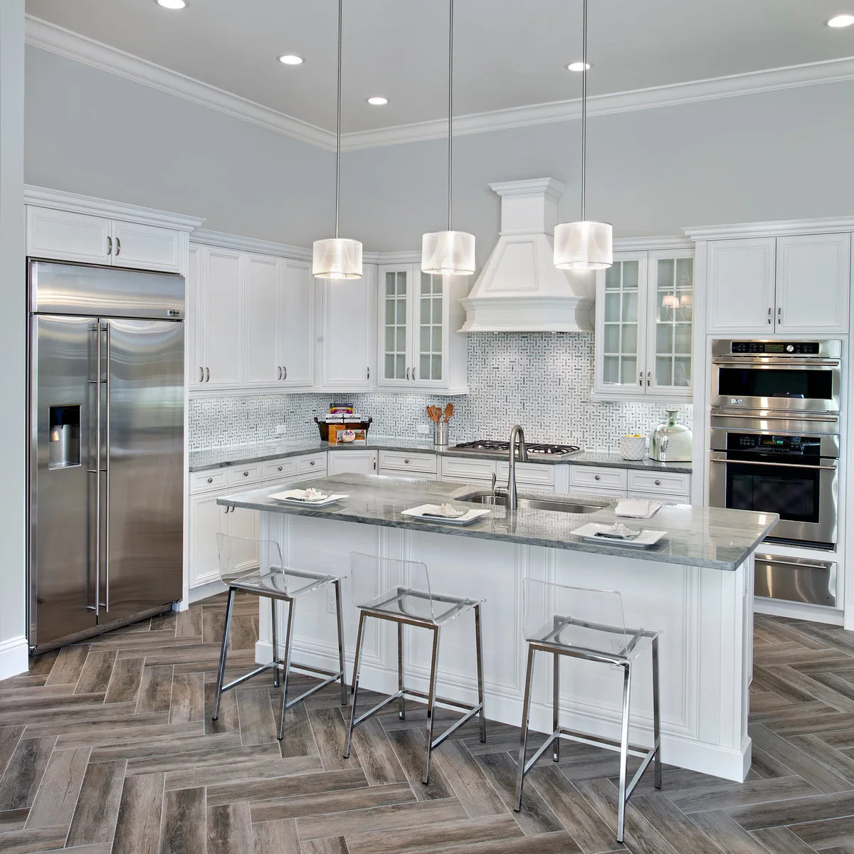 Clear low-backed kitchen stools on slim metal frames beside a pale island