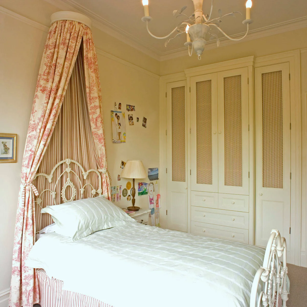 Traditional bedroom with pale full-height wardrobes, a metal bed and patterned canopy fabric