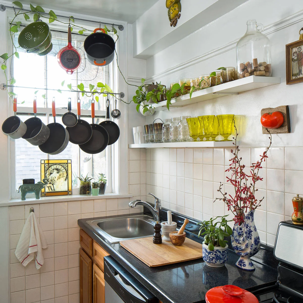 Small kitchen corner with hanging pans across a window and open shelves above the counter