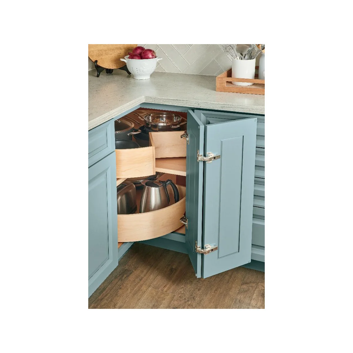 Blue corner cabinet with curved wooden carousel shelves holding cookware and tall jugs