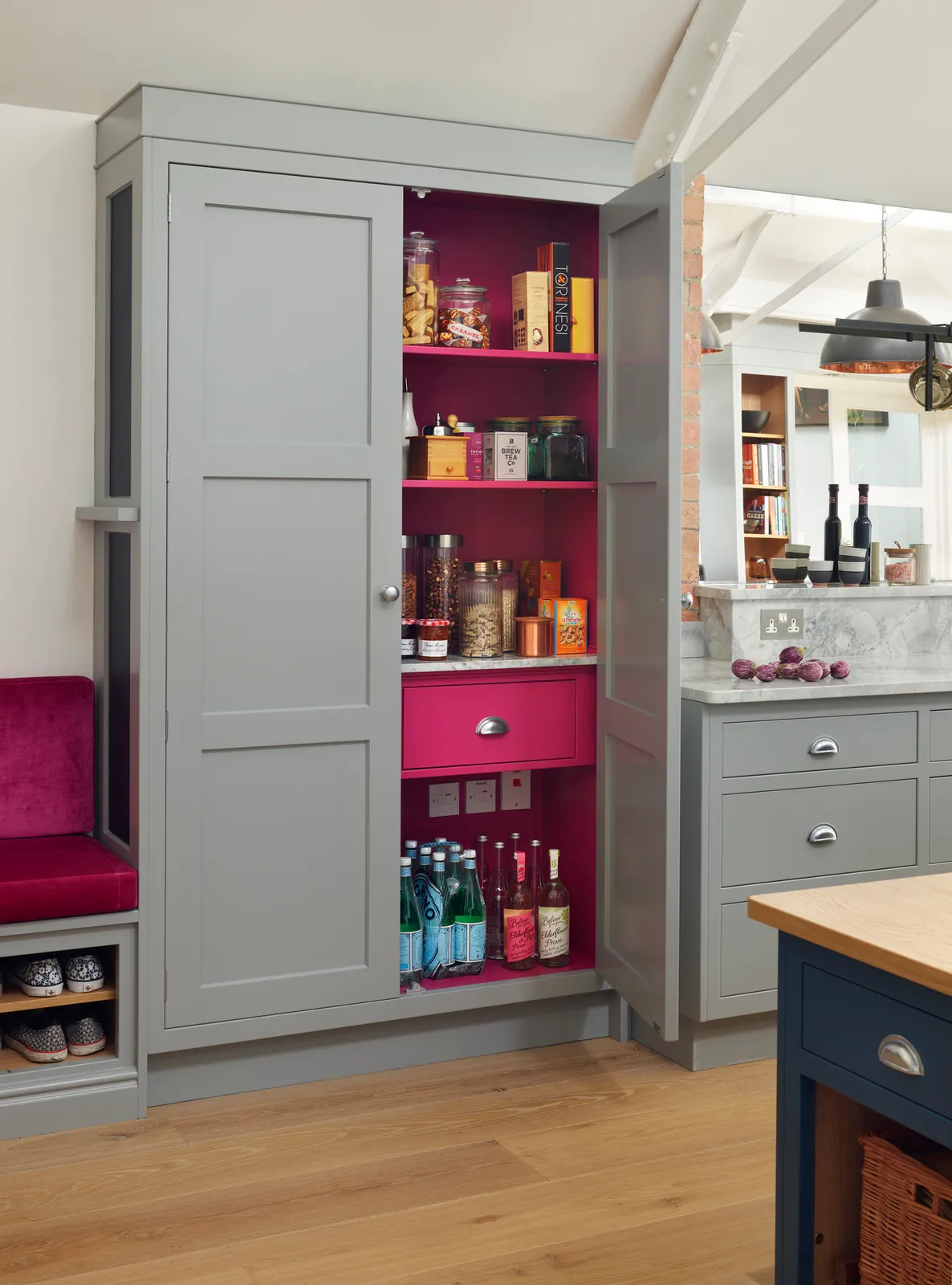 Gray larder with pink interior, jars above a drawer and bottles below