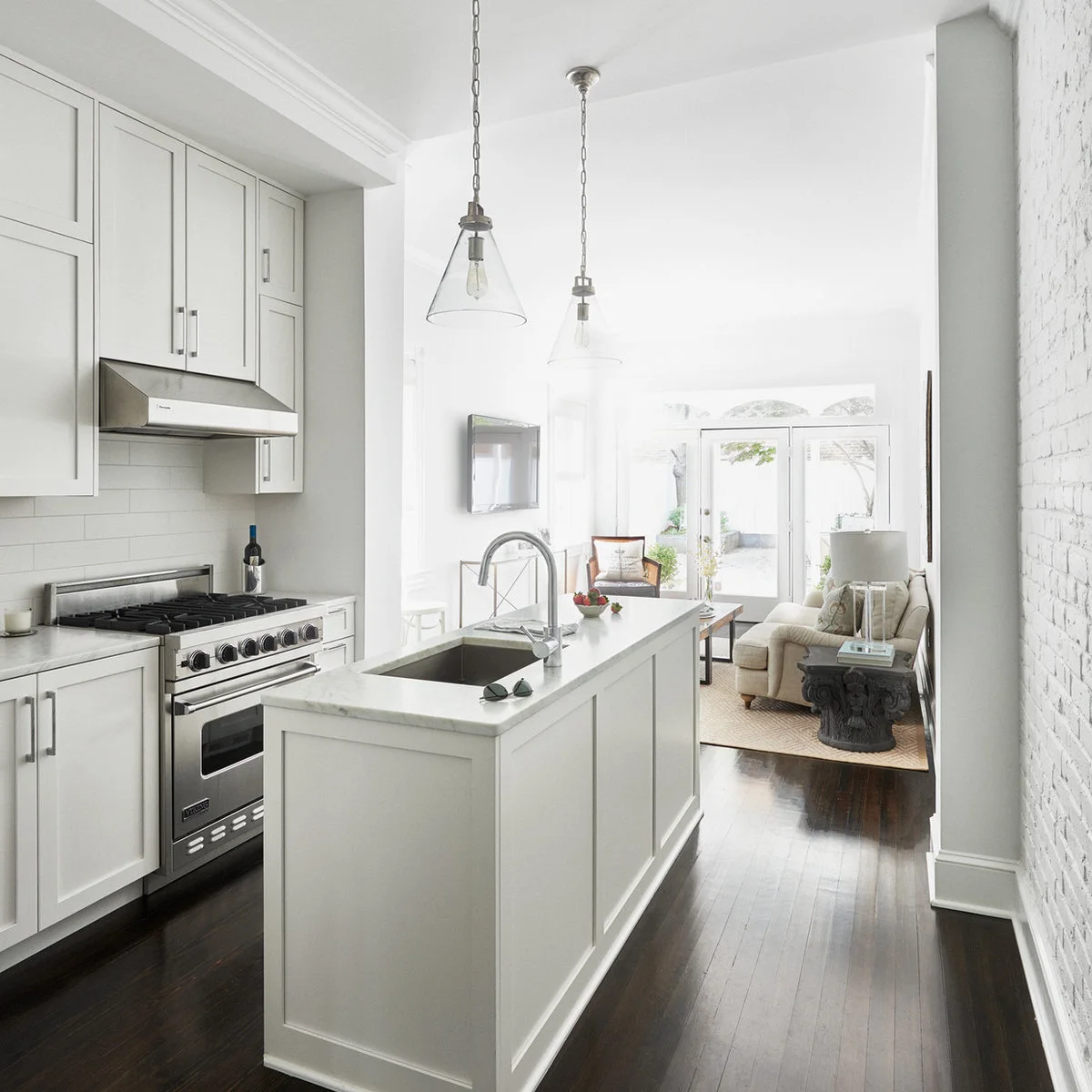 White kitchen with a narrow sink peninsula parallel to the cooking wall and a sitting area beyond