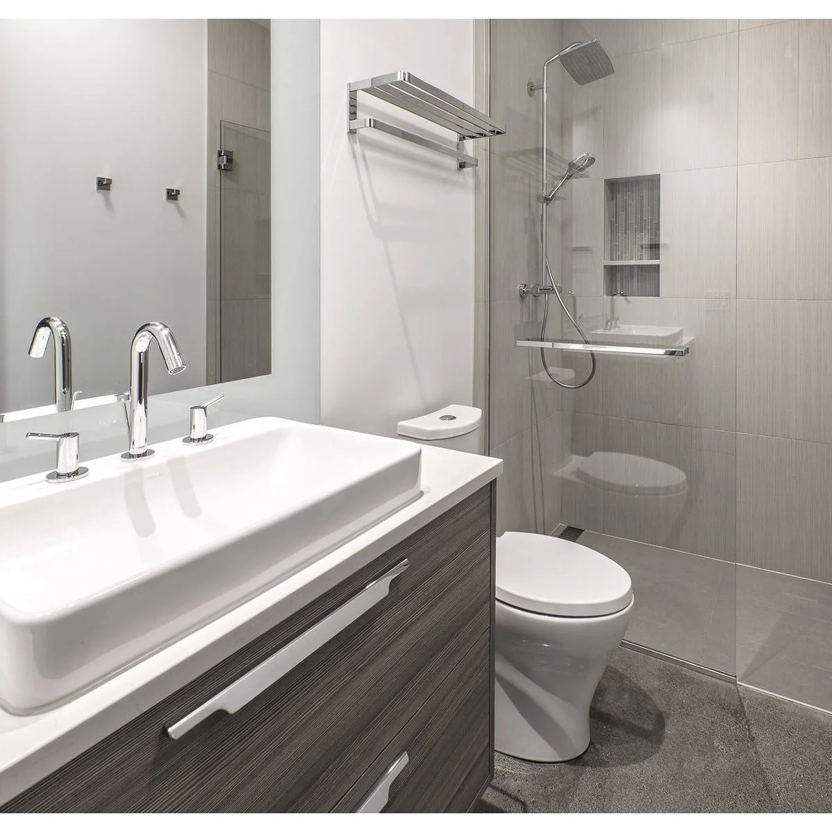 Slim gray-tiled glass shower with a handheld fitting and divided niche