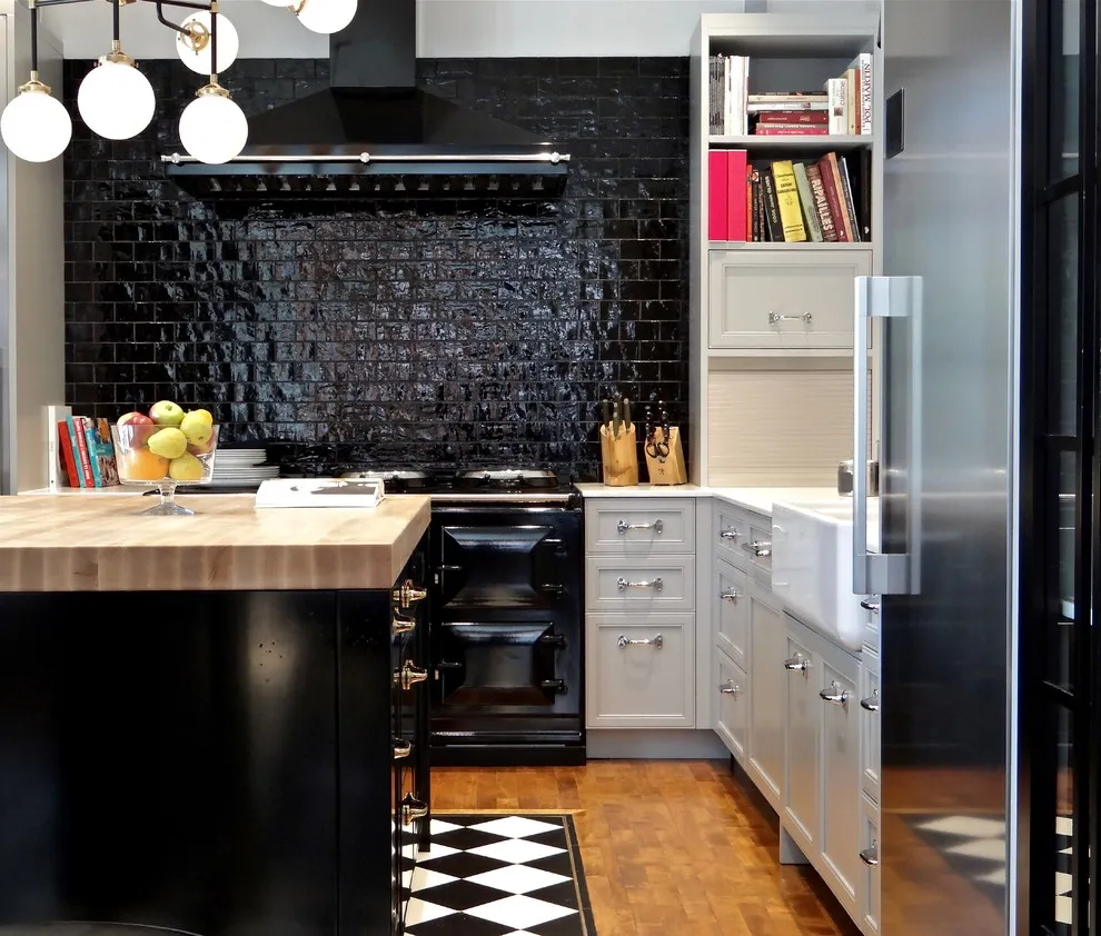 A black tile cooking wall sits beside white drawer fronts and a dark island