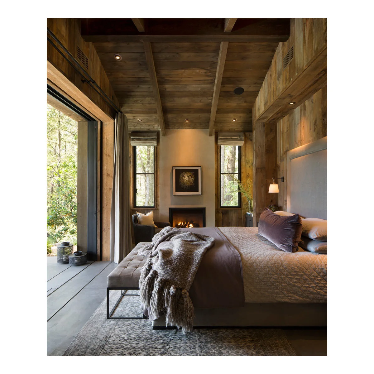 Wood-lined bedroom with pale headboard, chunky gray throw and bench at the foot