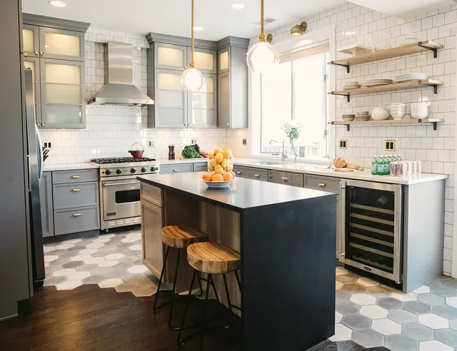 A black island includes timber seating details in a bright kitchen with pale cabinets.