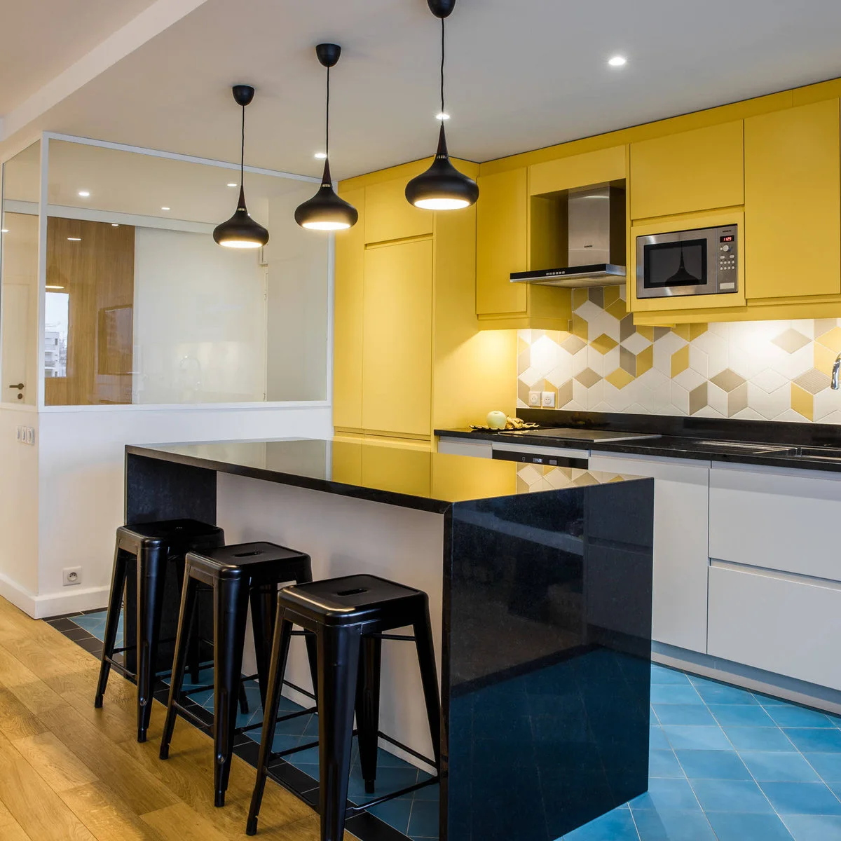 Yellow upper cabinets and tall storage above gray lower fronts with a geometric backsplash