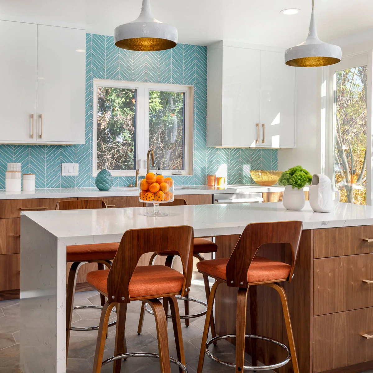 Aqua chevron-patterned tile sits between white upper cabinets and wood lower cabinets beside orange padded wood stools.