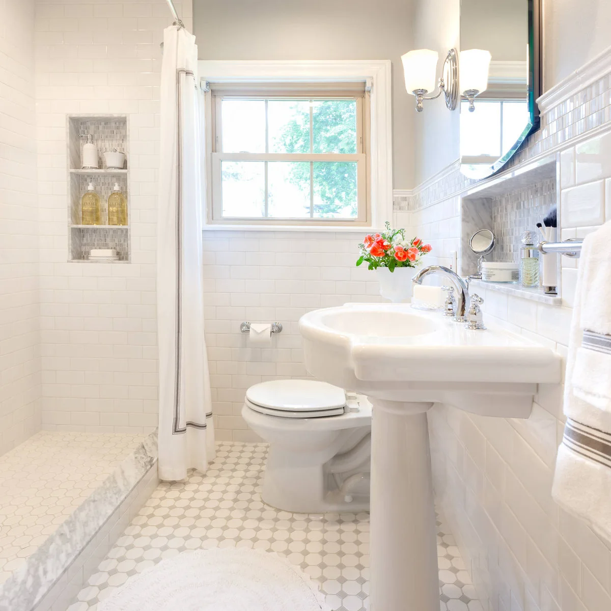 White tiled shower with an open white curtain beside a pedestal sink