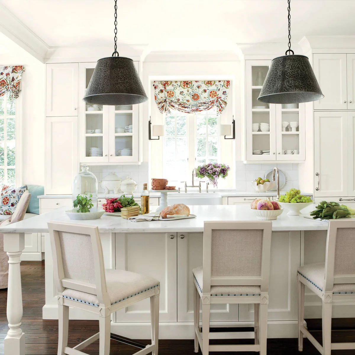 Floral fabric window treatments in a white kitchen with black hanging lights