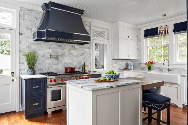 A dark lower cabinet sits beneath a matching substantial hood in a pale traditional kitchen.