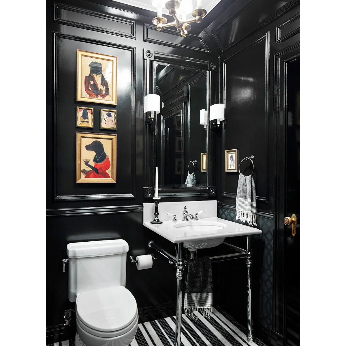 Gold-framed playful animal portraits on black paneling in a powder room