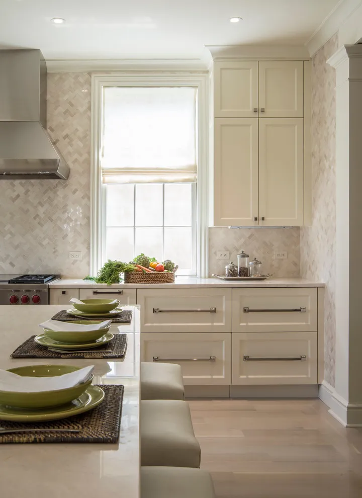 Beige cabinets and a pale stone counter frame a single kitchen window