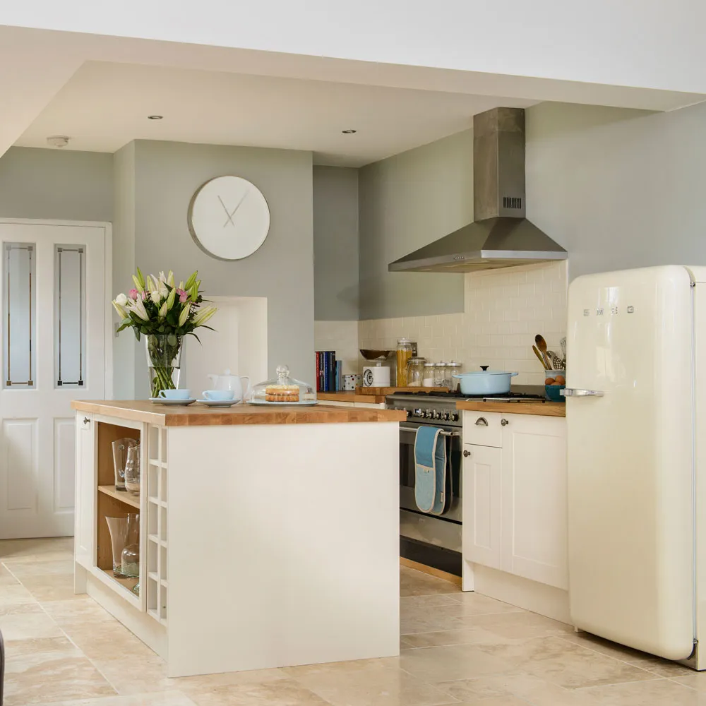 Cream lower cabinets and a small island sit beneath a sage-colored wall