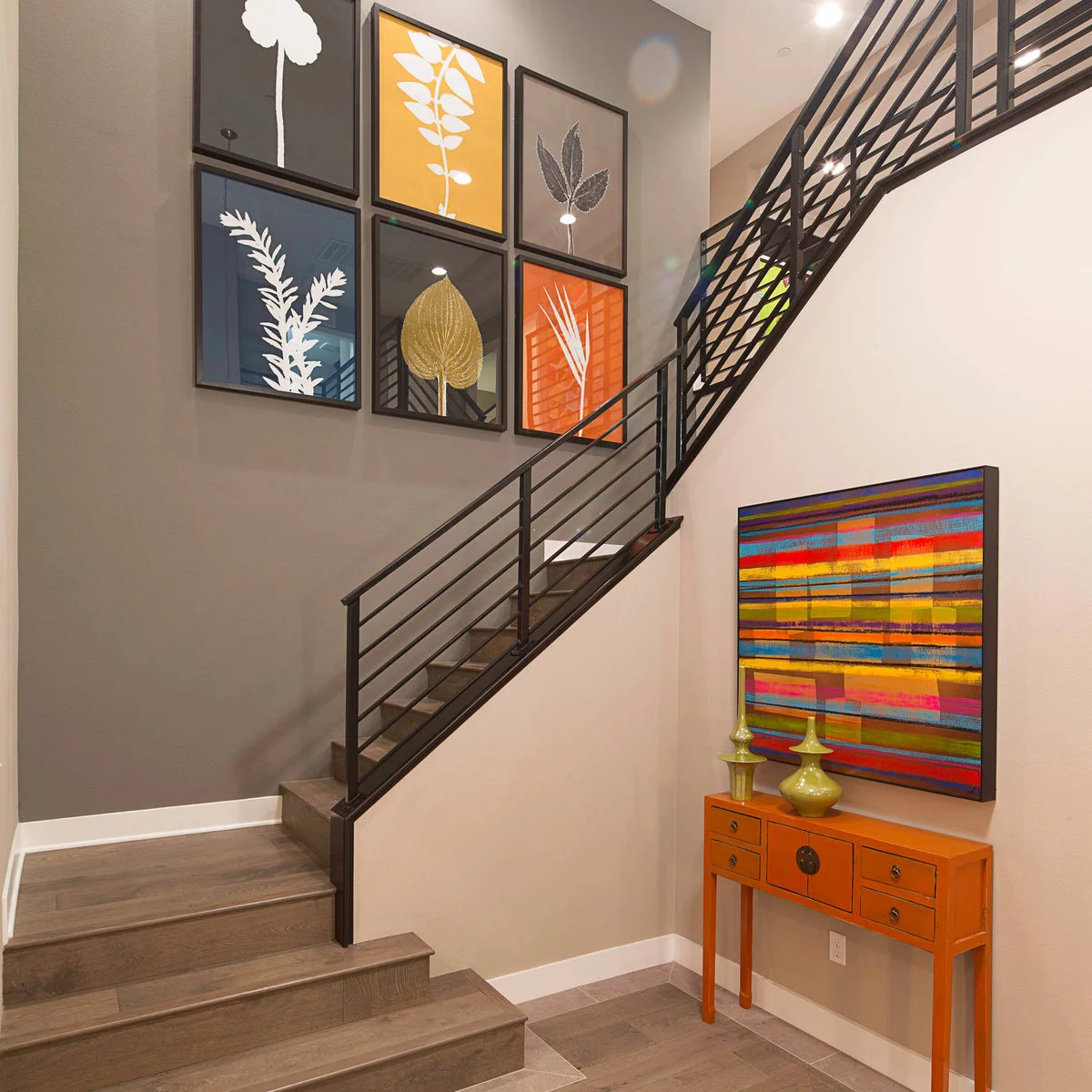 Six black-framed botanical prints form a grid beside a stair with horizontal black rails.