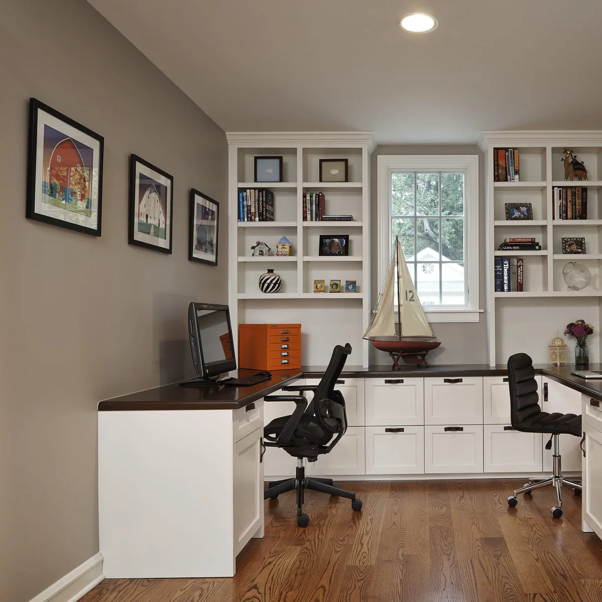 U-shaped fitted desk with white drawers, dark tops and two office chairs facing separate walls
