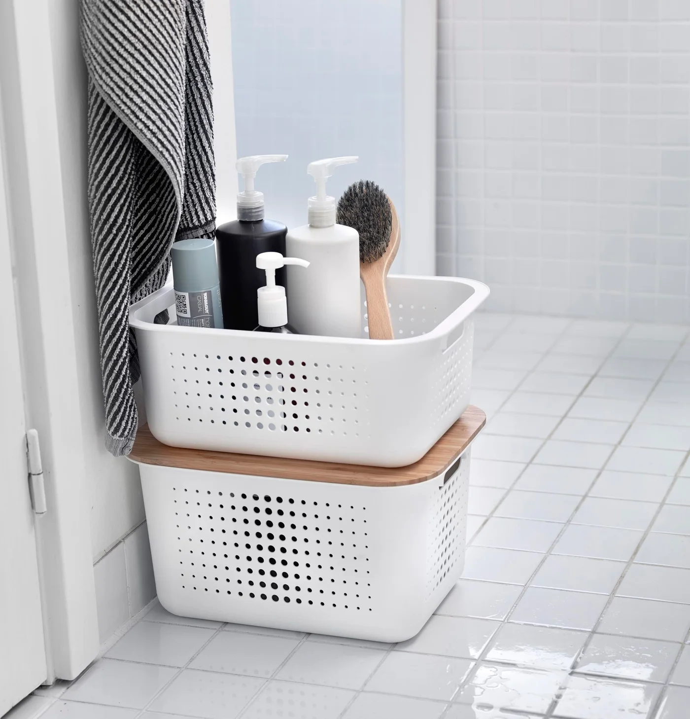 White perforated storage baskets stacked beside a bathroom doorway