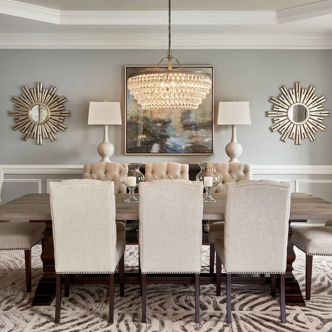 Pale rug with sweeping gray motifs beneath a wood dining table and cream upholstered chairs