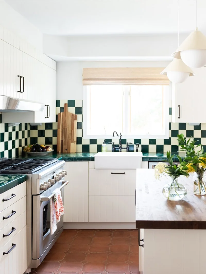 Terracotta hexagons sit below white cabinets and a green-and-white checked backsplash.