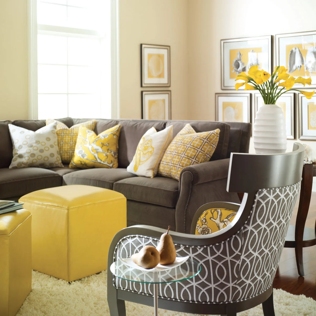 Gray sectional with yellow-and-white cushions, bright yellow stools and framed shell pictures with yellow backgrounds
