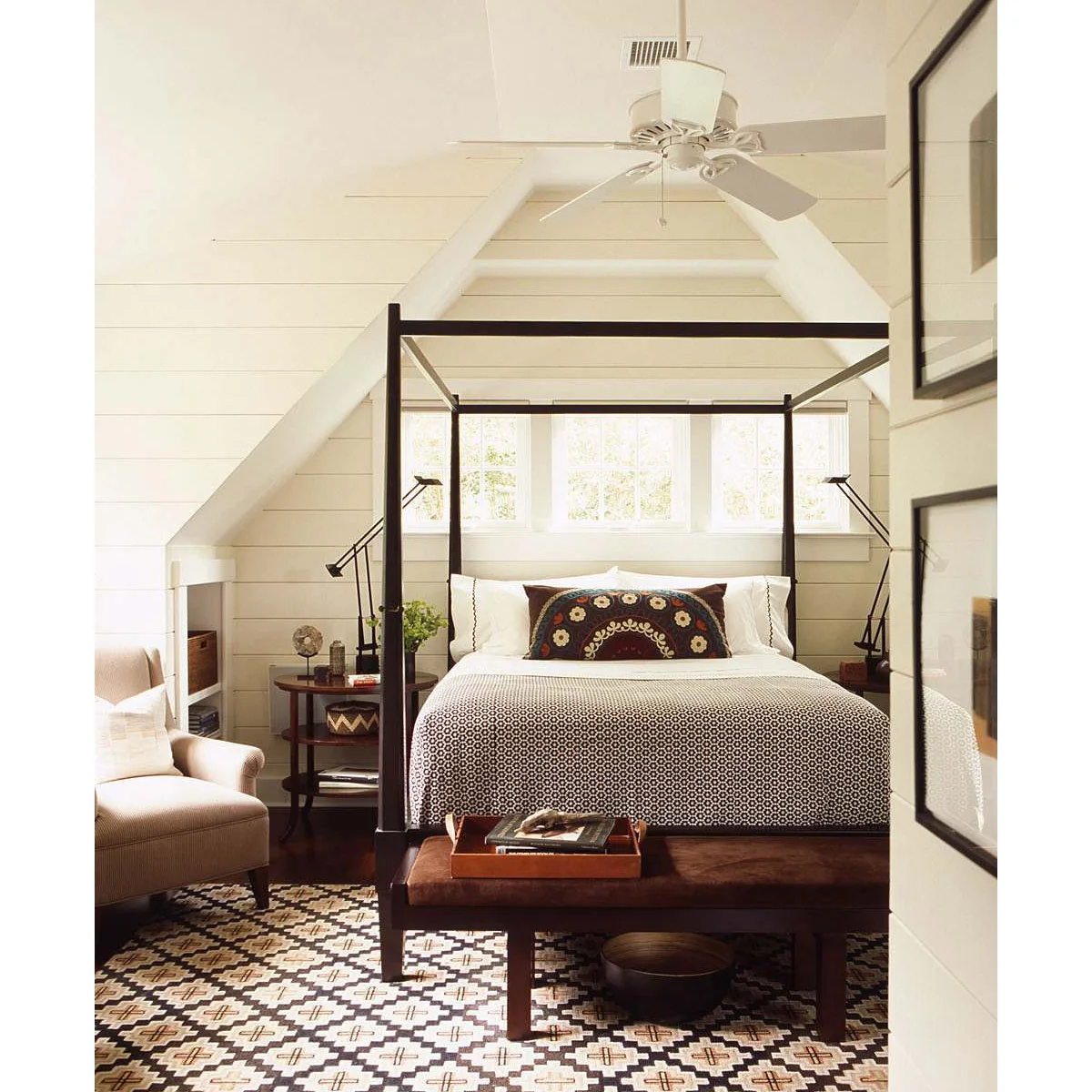 Compact attic bedroom with a dark four-poster bed, white boarded walls and adjustable bedside lamps