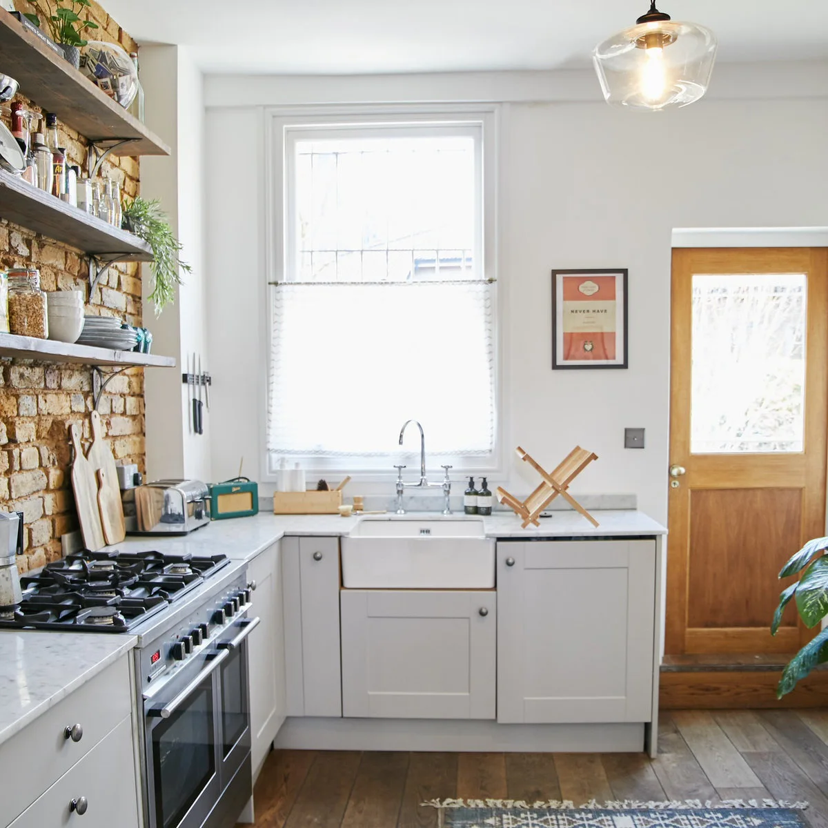 Small Victorian terrace kitchen with pale cabinets, a sink under the window and a wood-colored rear door
