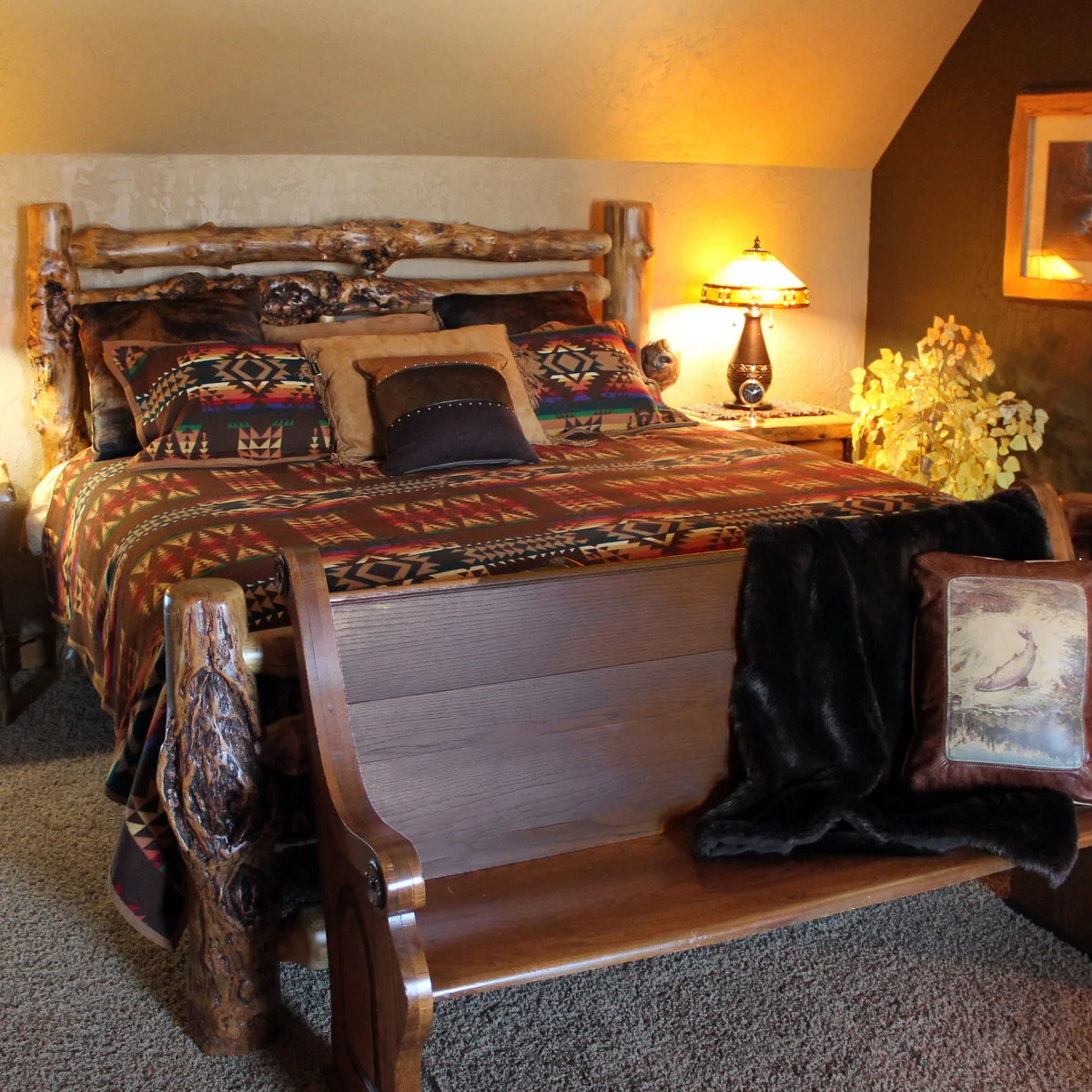 Rustic bedroom with a knotted log bed, richly colored geometric bedding and a wood bench at the foot