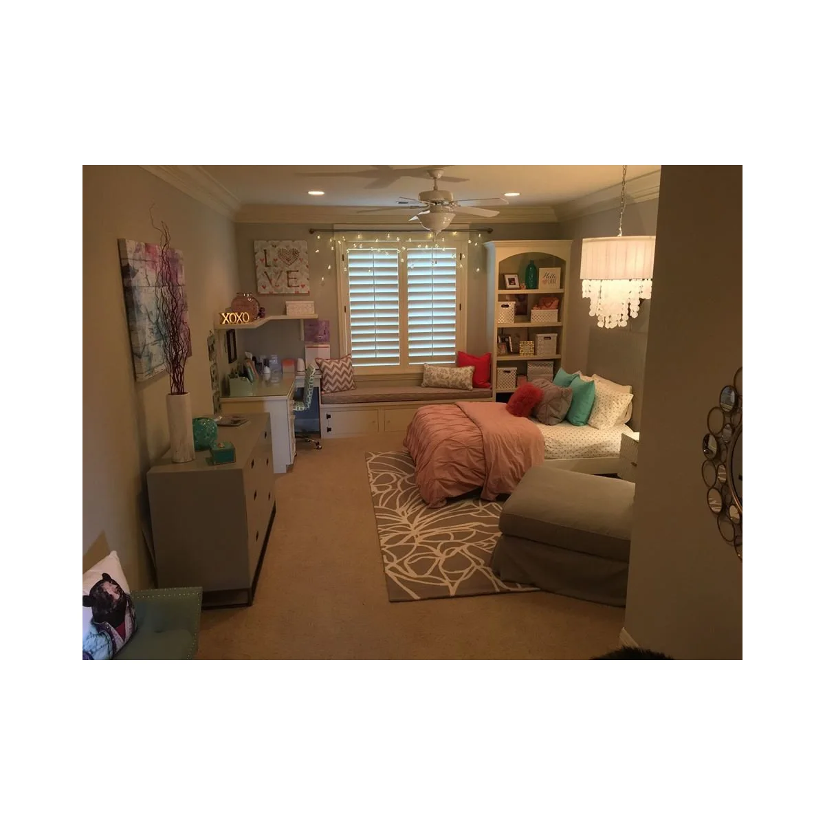 Teen bedroom with a window bench, white desk, open shelves and a pink-covered bed