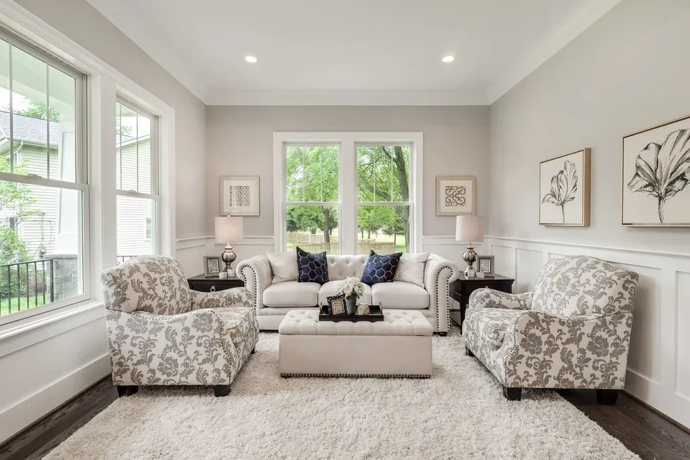 A light sofa faces two patterned armchairs around an upholstered ottoman