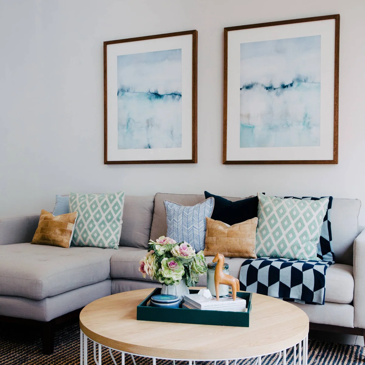 Gray chaise sofa with blue and teal cushions, geometric textiles and a small round table