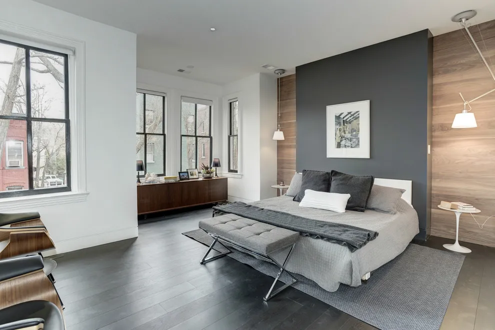 A dark central wall sits behind a bed between warmer timber wall sections