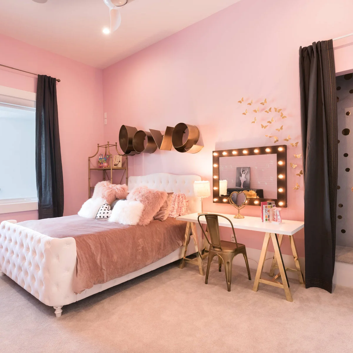 Pink bedroom with white tufted bed, long trestle desk and dark curtains