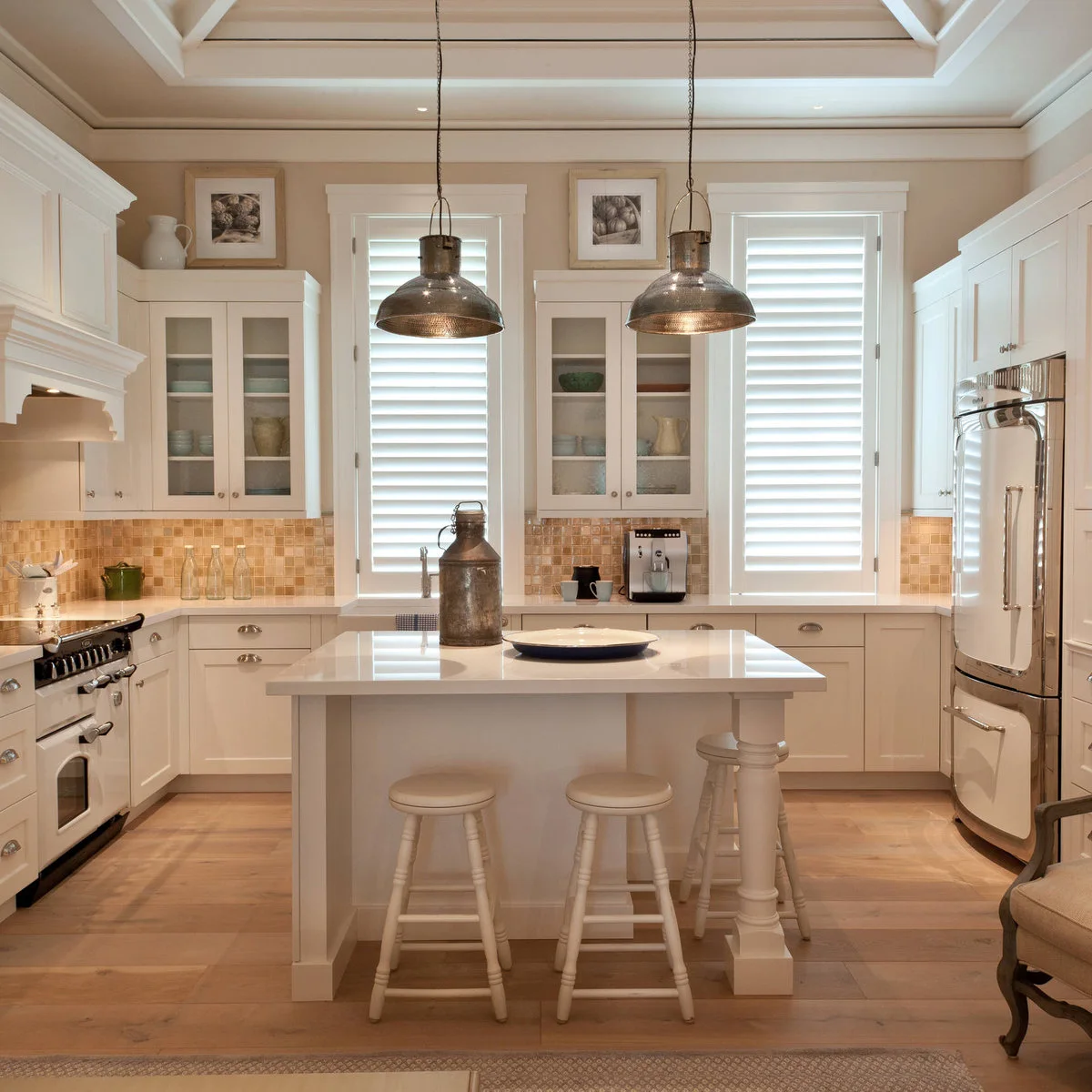 A white refrigerator sits beneath white cupboard doors in a kitchen with glass-front cabinets and an island.