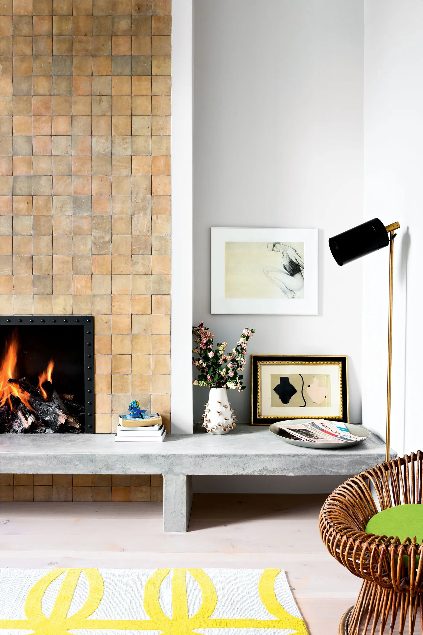 Golden square-tiled fireplace breast with black opening, pale hearth extension and dark woven chair