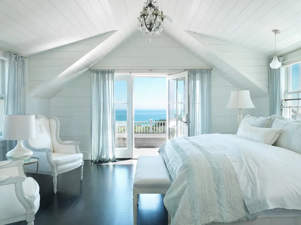 Dark wood boards run through a bright bedroom with white walls and pale bedding