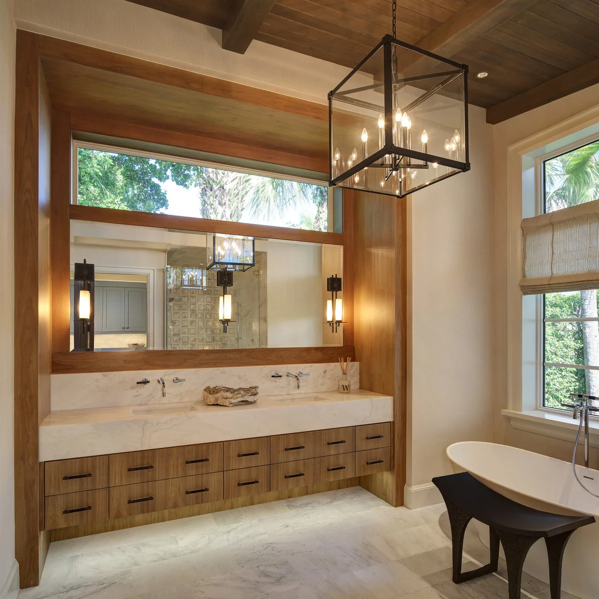 Long wood vanity with a pale countertop, a shallow irregular tray and a reed diffuser near the outer end.