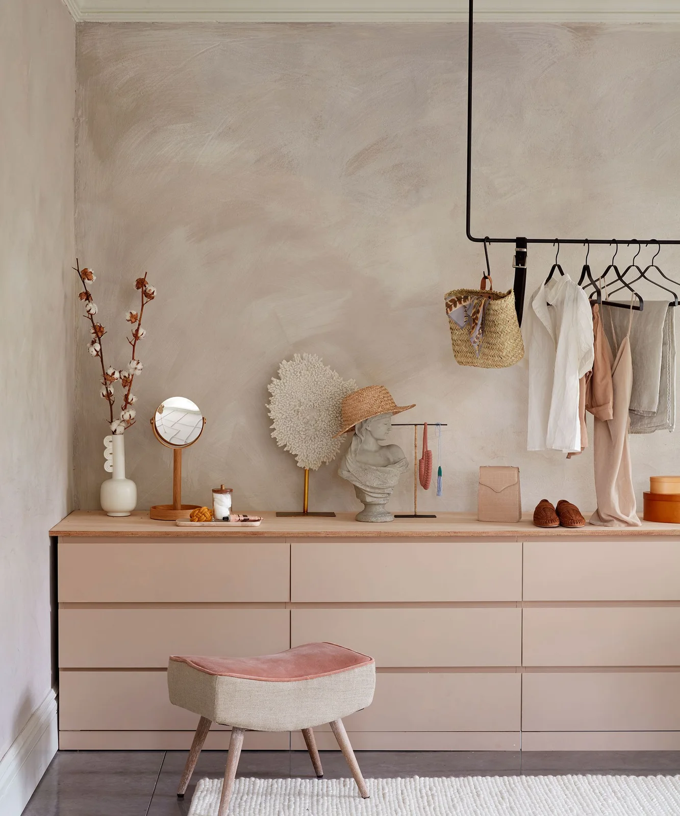 Pale pink drawer chests under a continuous wooden top in a dressing area