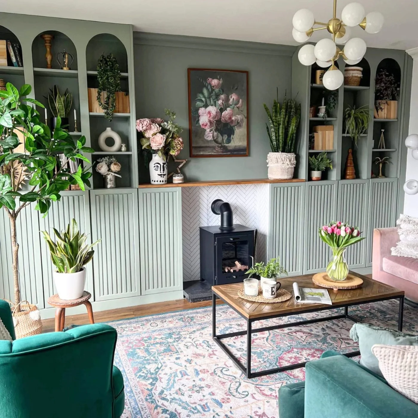 Sage green built-in bookcases with arched openings and fluted lower doors around a fireplace