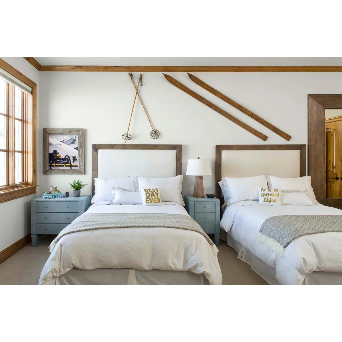 Twin bedroom with a narrow blue bedside chest between two pale upholstered beds