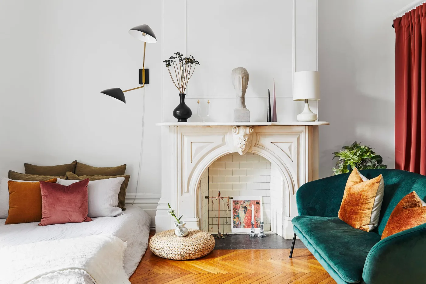 Pale fireplace with two dark red tapers on the mantel, sculptural objects and artwork inside the opening.