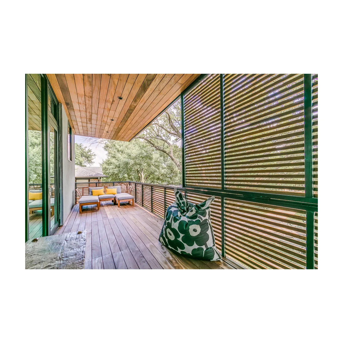 Long horizontal slatted screens run beside a timber balcony with a bench and distant corner seating