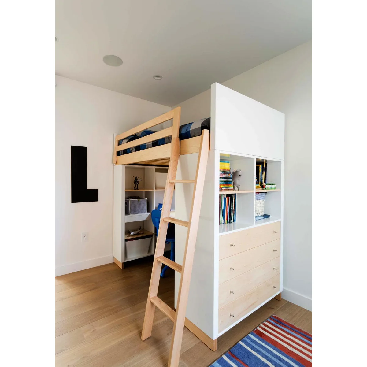 White and pale wood loft bed with a drawer chest and book cubbies at one end and a desk underneath.