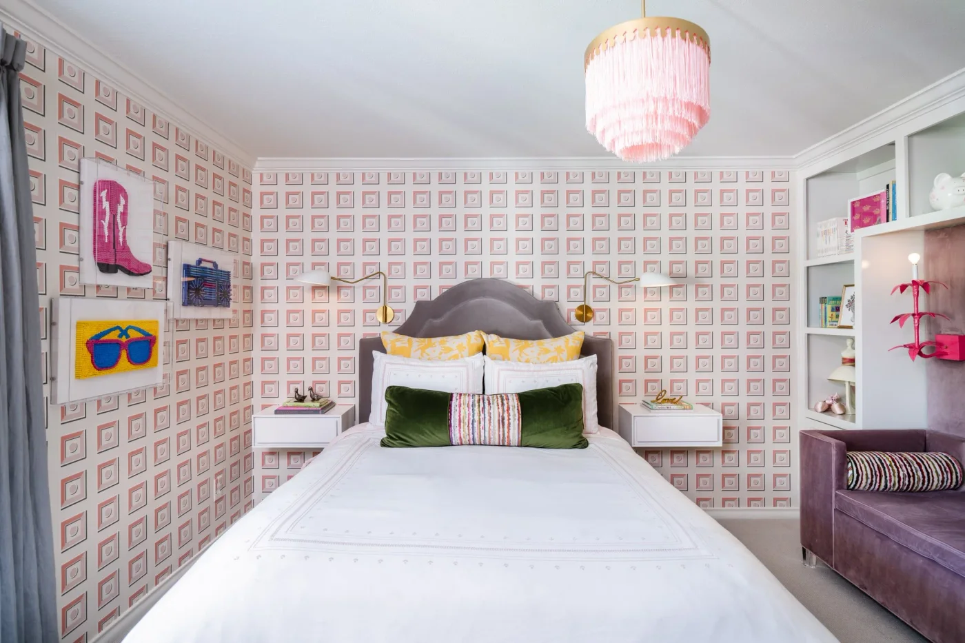 Pink geometric wallpaper wraps a bedroom with a curved gray headboard, white bedding and a pink pendant.