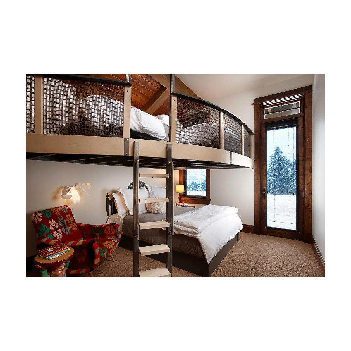 Metal loft bed with mesh sides above a lower bed, a patterned armchair at the left and a central ladder.