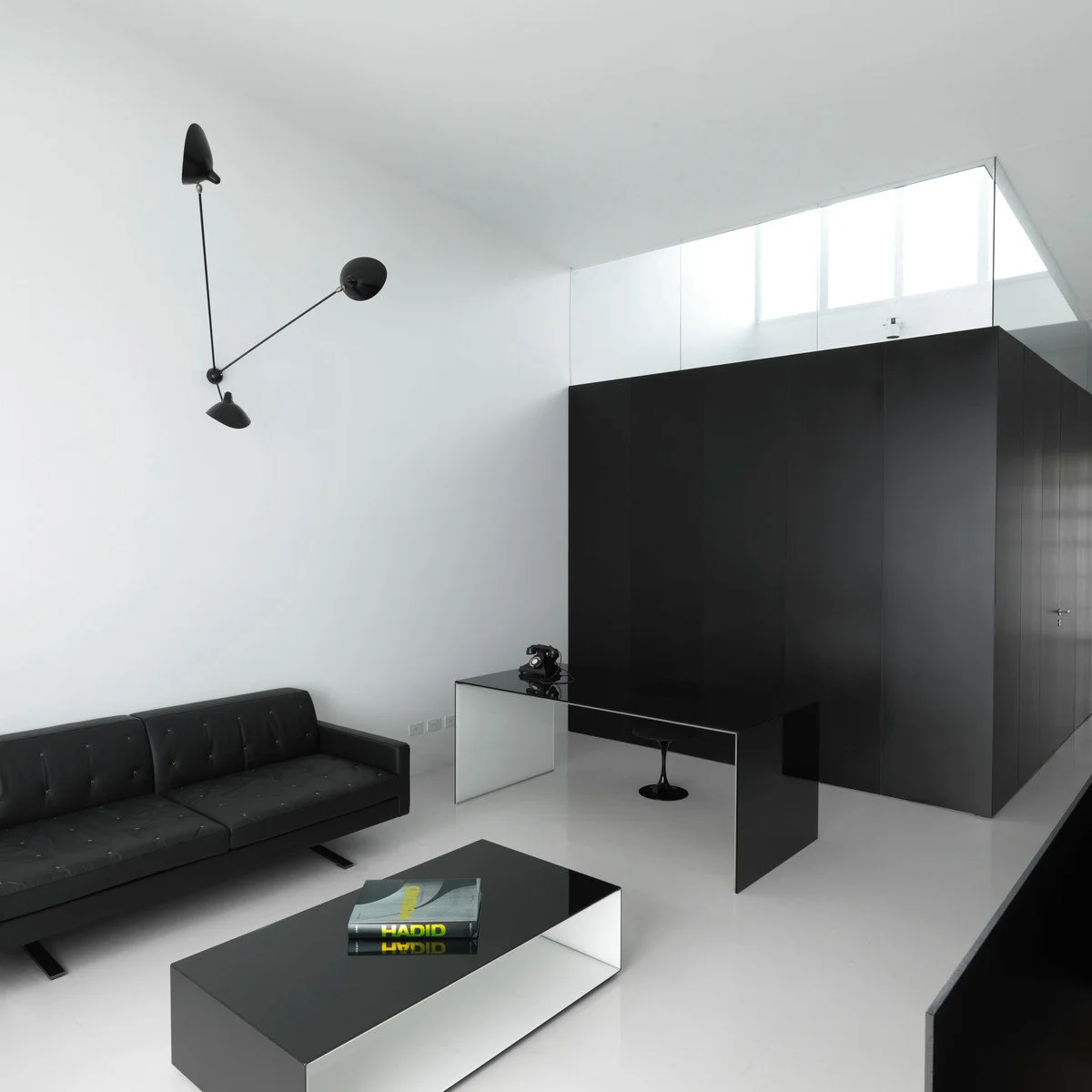 Minimal pale living space with black sofa, black wall volume and reflective tables